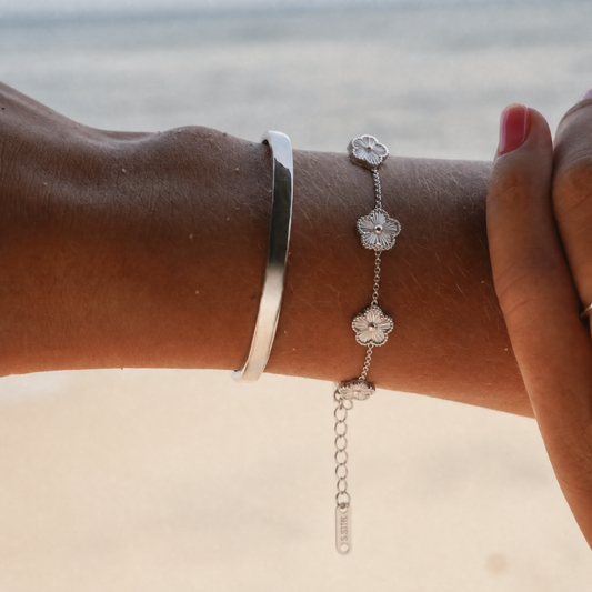 Trèfle Bracelet Silver & Pearl worn on model wrist at the beach with silver tone cuff bangle