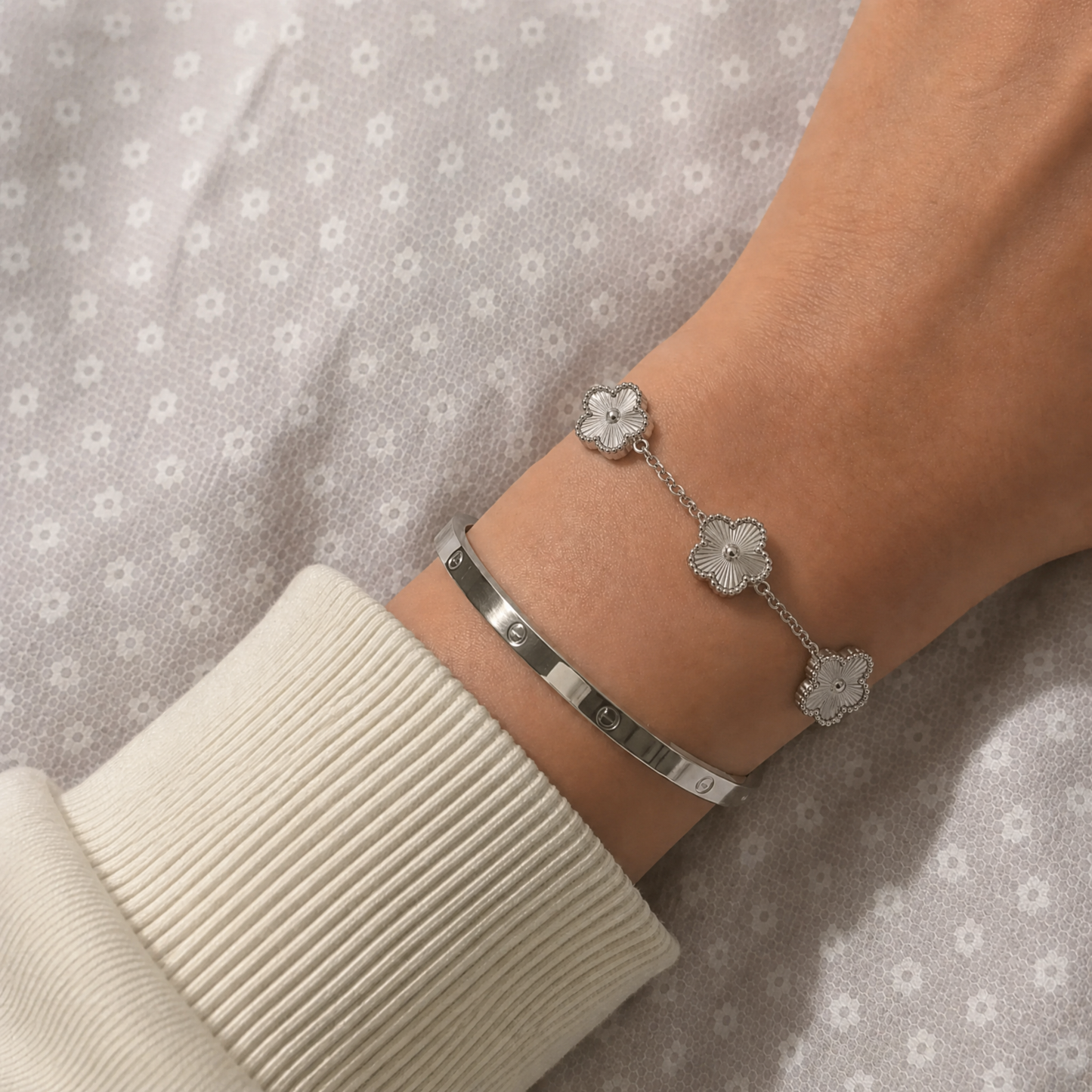Trèfle Bracelet Silver & Pearl on wrist with silver tone bangle, cozy bedroom lifestyle shot