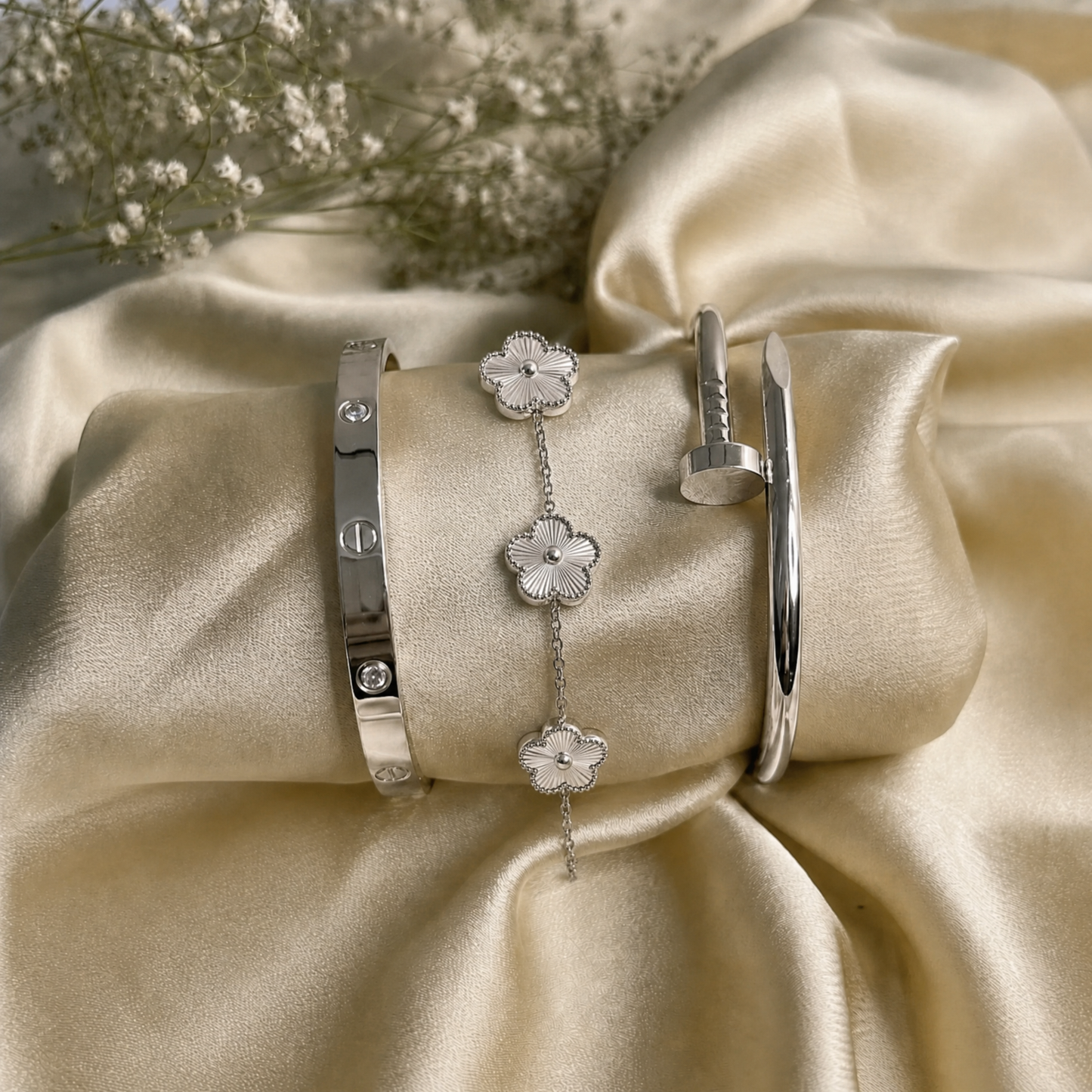 Trèfle Bracelet Silver & Pearl flat lay on champagne satin with silver tone bangles and dried flowers