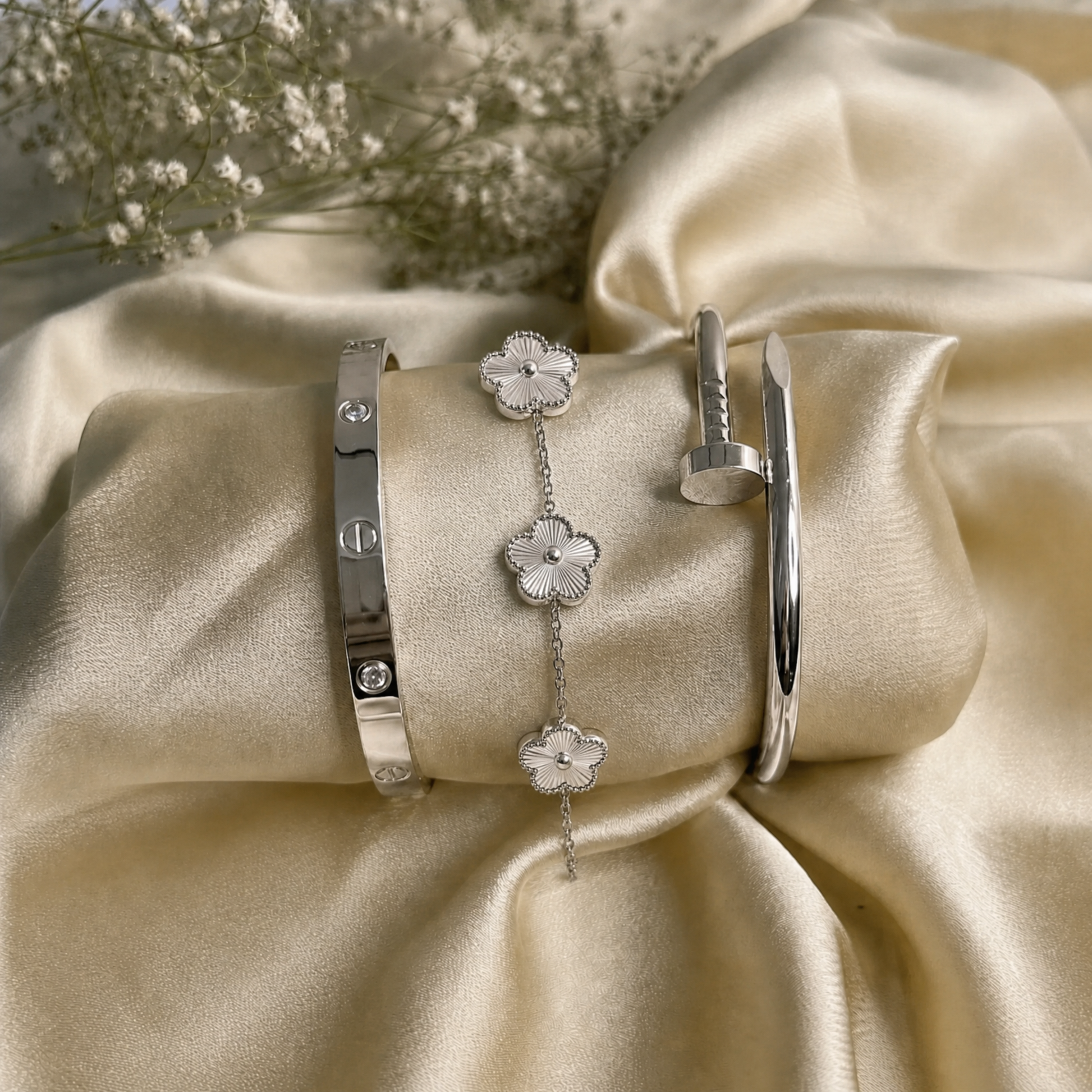 Trèfle Bracelet Silver & Pearl flat lay on champagne satin with silver tone bangles and dried flowers