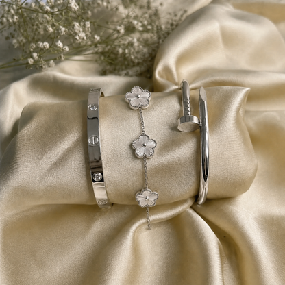 Trèfle Bracelet Silver & Pearl flat lay on champagne satin with silver tone bangles and dried flowers