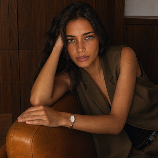 Passy Watch Silver on model wrist, silver tone bangle watch worn leaning on a leather armchair