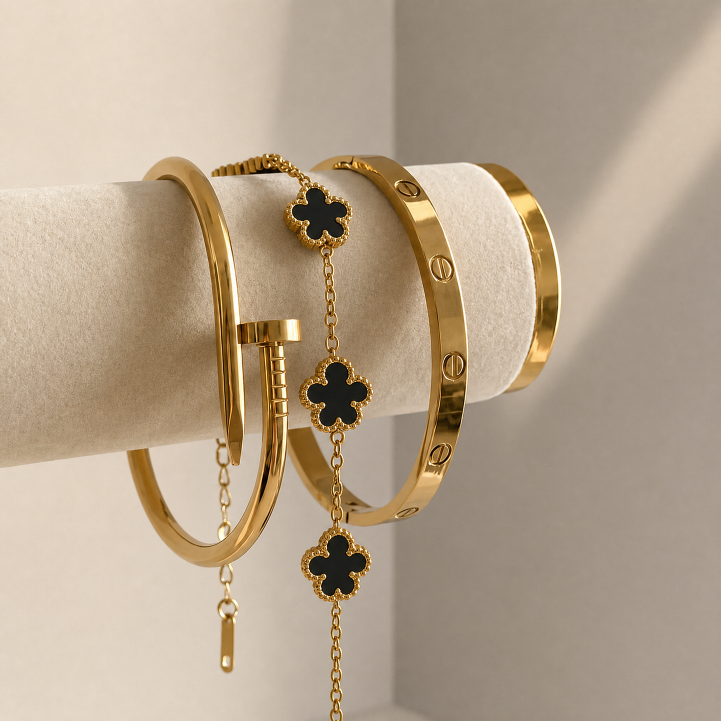 Trèfle Bracelet Gold & Onyx draped on jewelry cushion with gold tone bangles, studio detail