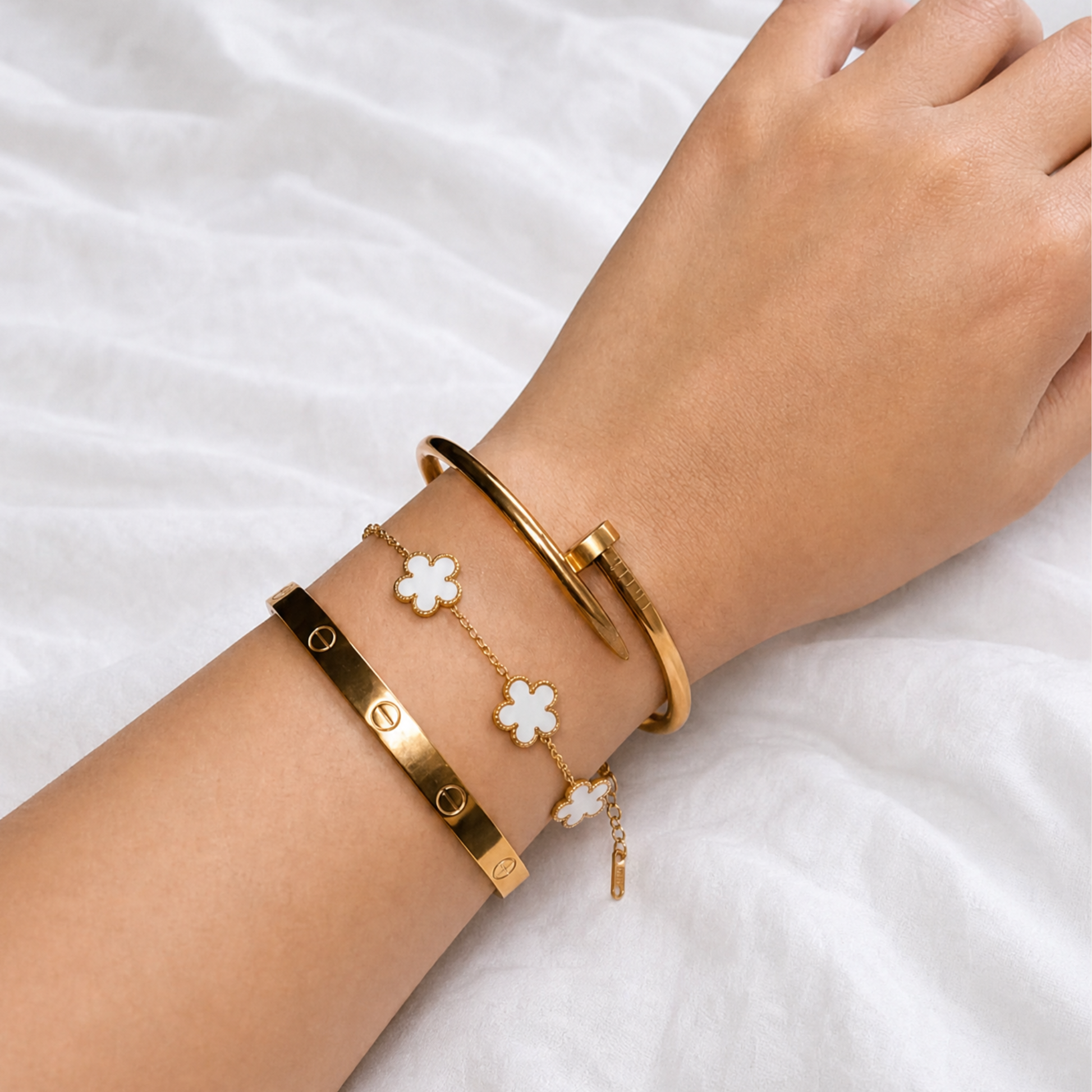 Trèfle Bracelet Gold & Pearl on wrist stacked with gold tone bangles, white knit sleeve