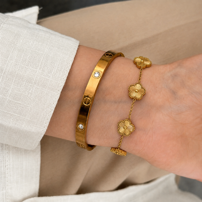 Trèfle Bracelet Gold five-leaf clover bracelet stacked with gold tone bangle on wrist